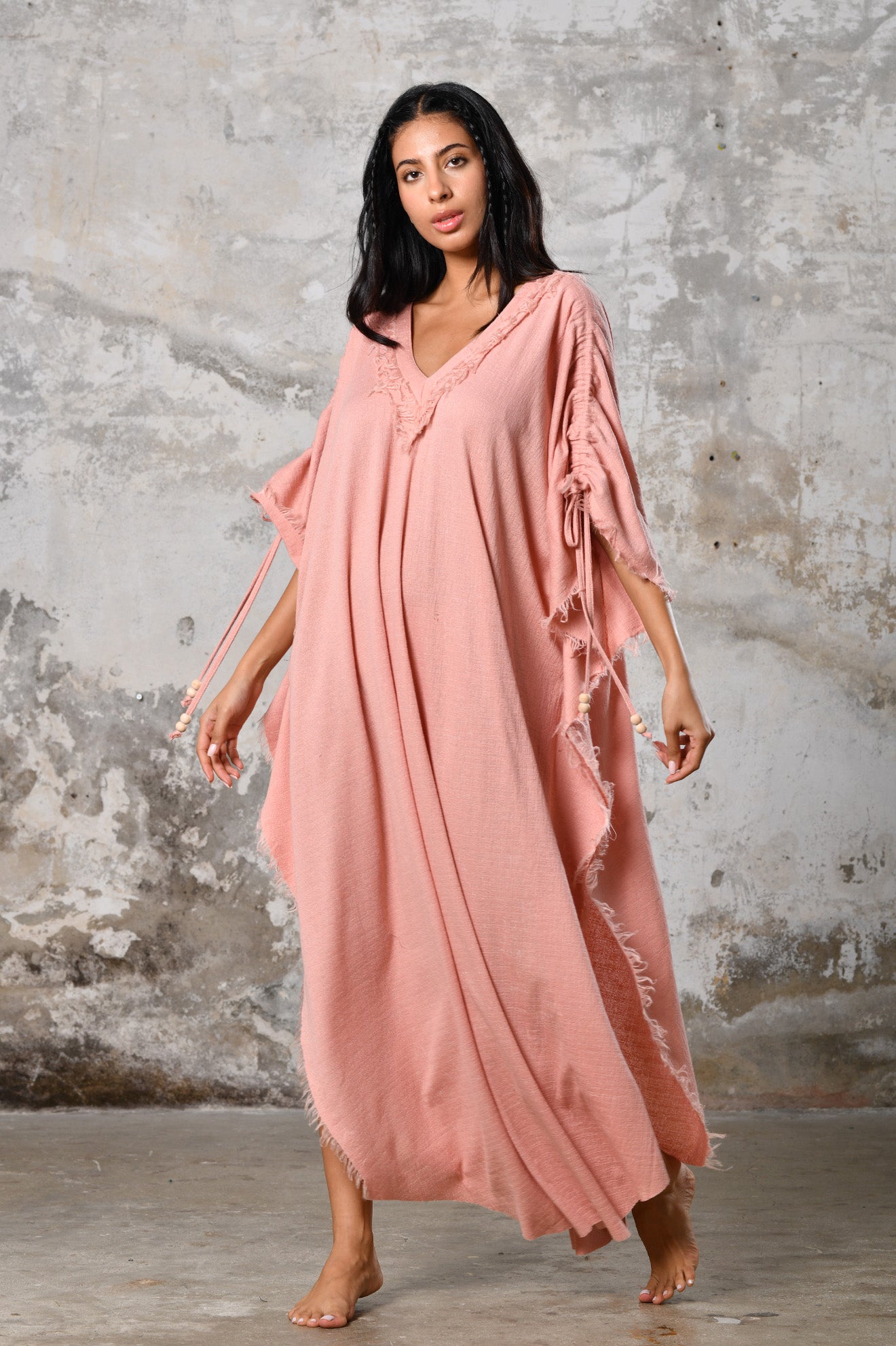 A versatile, pink earthy goddess dress that embodies boho-chic style. Crafted from the softest cotton fabric, this garment offers both comfort and a fashion statement. The dress can be worn in two distinct styles, either as a kaftan or a sultry dress, with a simple change in the way you put it on. Its natural and ethereal design exudes a warm, comforting feeling against your skin, making it a must-have addition to your wardrobe for those seeking a harmonious blend of style and comfort.