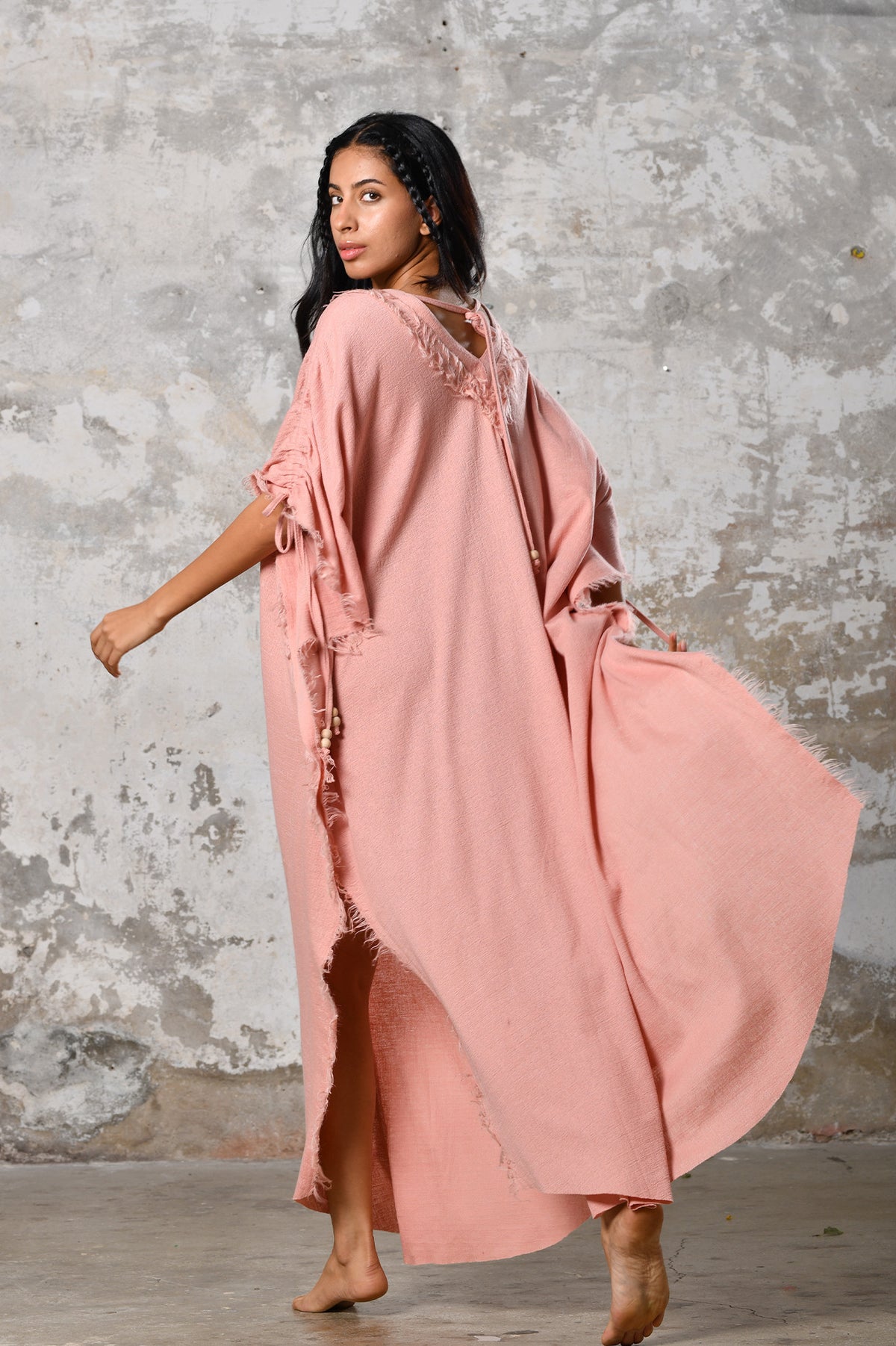 A versatile, pink earthy goddess dress that embodies boho-chic style. Crafted from the softest cotton fabric, this garment offers both comfort and a fashion statement. The dress can be worn in two distinct styles, either as a kaftan or a sultry dress, with a simple change in the way you put it on. Its natural and ethereal design exudes a warm, comforting feeling against your skin, making it a must-have addition to your wardrobe for those seeking a harmonious blend of style and comfort.