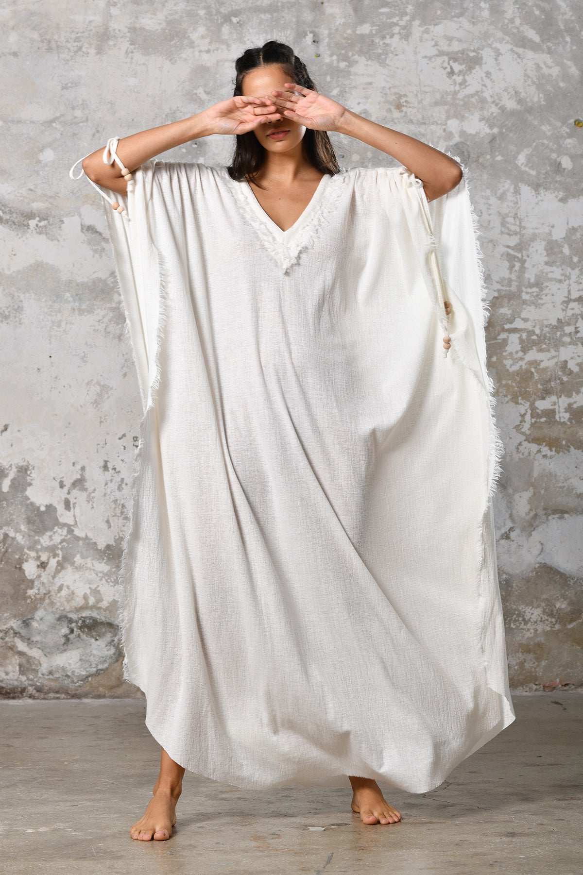 A versatile, White earthy goddess dress that embodies boho-chic style. Crafted from the softest cotton fabric, this garment offers both comfort and a fashion statement. The dress can be worn in two distinct styles, either as a kaftan or a sultry dress, with a simple change in the way you put it on. Its natural and ethereal design exudes a warm, comforting feeling against your skin, making it a must-have addition to your wardrobe for those seeking a harmonious blend of style and comfort.