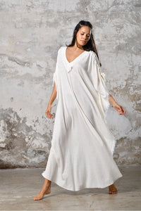 A versatile, White earthy goddess dress that embodies boho-chic style. Crafted from the softest cotton fabric, this garment offers both comfort and a fashion statement. The dress can be worn in two distinct styles, either as a kaftan or a sultry dress, with a simple change in the way you put it on. Its natural and ethereal design exudes a warm, comforting feeling against your skin, making it a must-have addition to your wardrobe for those seeking a harmonious blend of style and comfort.