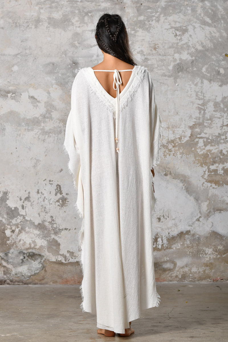 A versatile, White earthy goddess dress that embodies boho-chic style. Crafted from the softest cotton fabric, this garment offers both comfort and a fashion statement. The dress can be worn in two distinct styles, either as a kaftan or a sultry dress, with a simple change in the way you put it on. Its natural and ethereal design exudes a warm, comforting feeling against your skin, making it a must-have addition to your wardrobe for those seeking a harmonious blend of style and comfort.