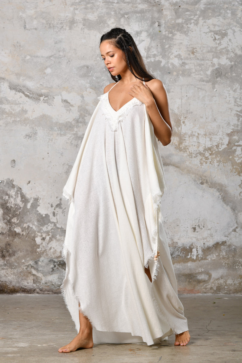 A versatile, White earthy goddess dress that embodies boho-chic style. Crafted from the softest cotton fabric, this garment offers both comfort and a fashion statement. The dress can be worn in two distinct styles, either as a kaftan or a sultry dress, with a simple change in the way you put it on. Its natural and ethereal design exudes a warm, comforting feeling against your skin, making it a must-have addition to your wardrobe for those seeking a harmonious blend of style and comfort.