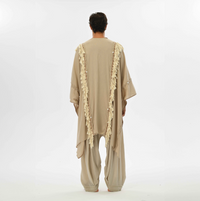 Beige boho poncho for women, made from organic cotton with fringes and braids, ideal for casual wear, festivals, or resort vacations.