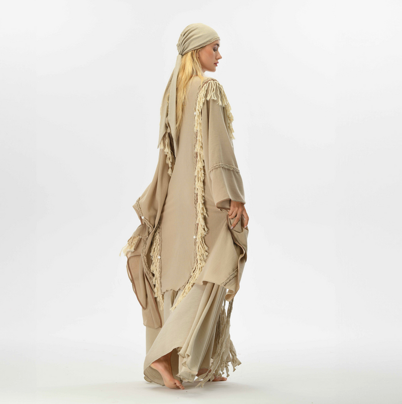 Fringe boho poncho in beige, crafted from organic cotton with handmade tassels, ideal for adding a stylish touch to casual or festival outfits.