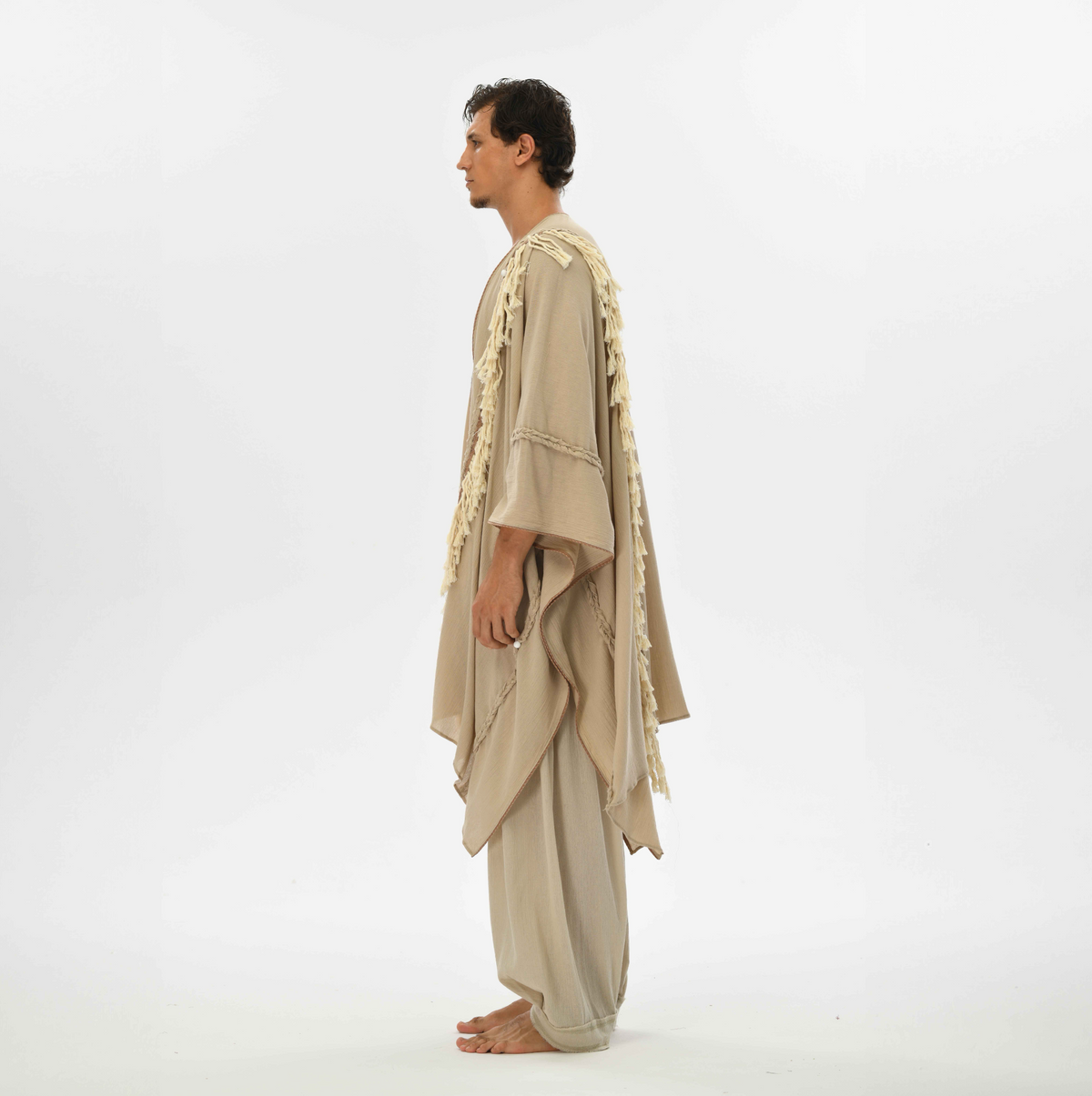 Boho fringe cape in beige, made from organic cotton with handmade tassels and braided details, perfect for casual wear or festival fashion.