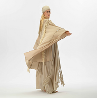 Beige boho cape with handmade fringe and braids, made from organic cotton, ideal for shamanic-inspired festival wear or casual bohemian outfits.