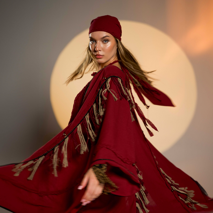 Organic cotton kimono-style poncho in red, featuring braided details and fringes. Perfect for women’s boho chic fashion, fits sizes XS to XXL.