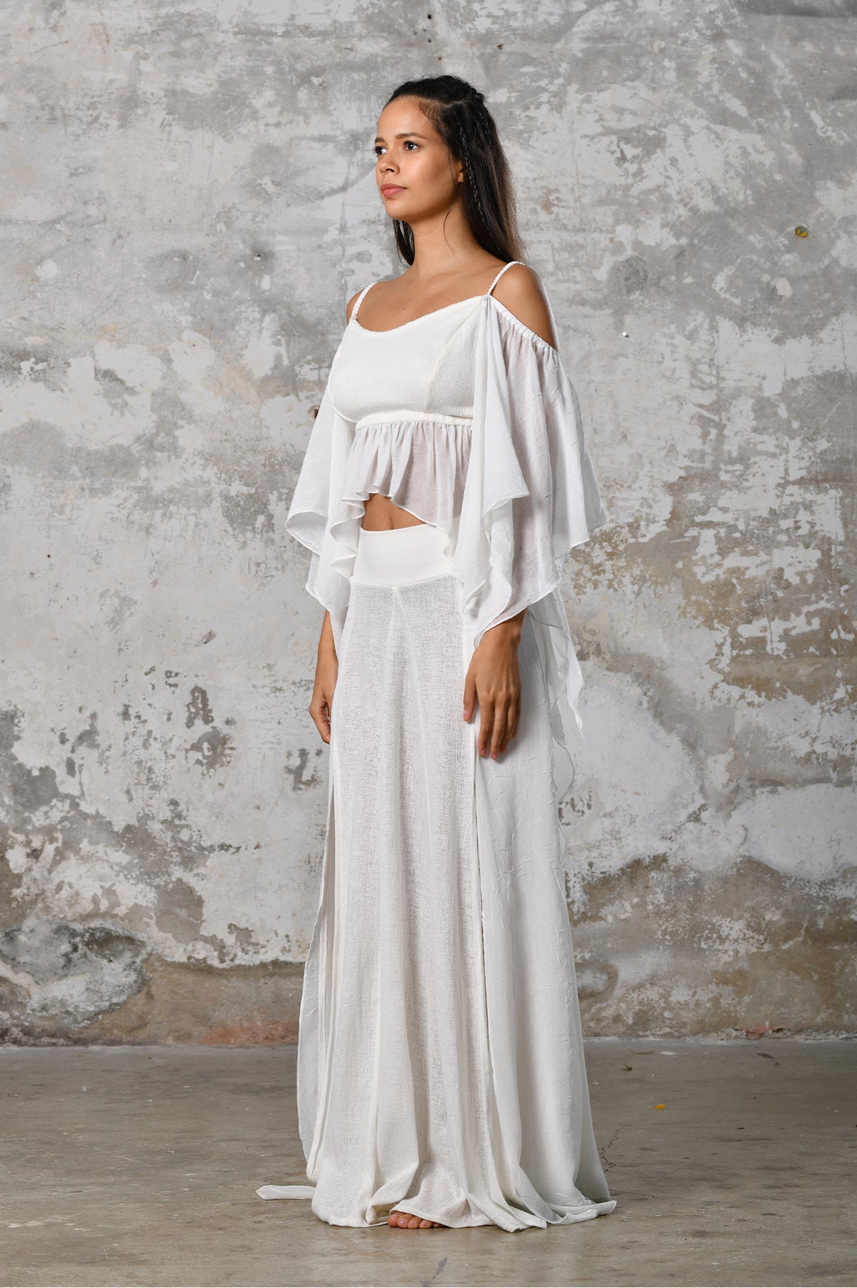 An enchanting Bohemian Venus white, perfect for boho and festival-inspired looks, exuding a goddess-like quality. The flowy fabric and intricate side details create an ethereal, bohemian style perfect for Burning Man and other occasions. This garment is an ethically crafted gem