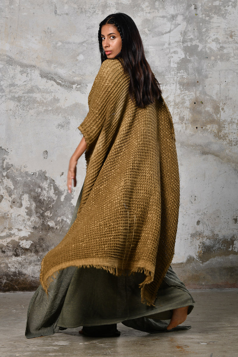 A person wearing the Waffle Poncho, a cozy bohemian-inspired garment made from Turkish cotton, in a serene autumn setting, surrounded by colorful leaves and warm hues, embodying the essence of autumn fashion and comfort.