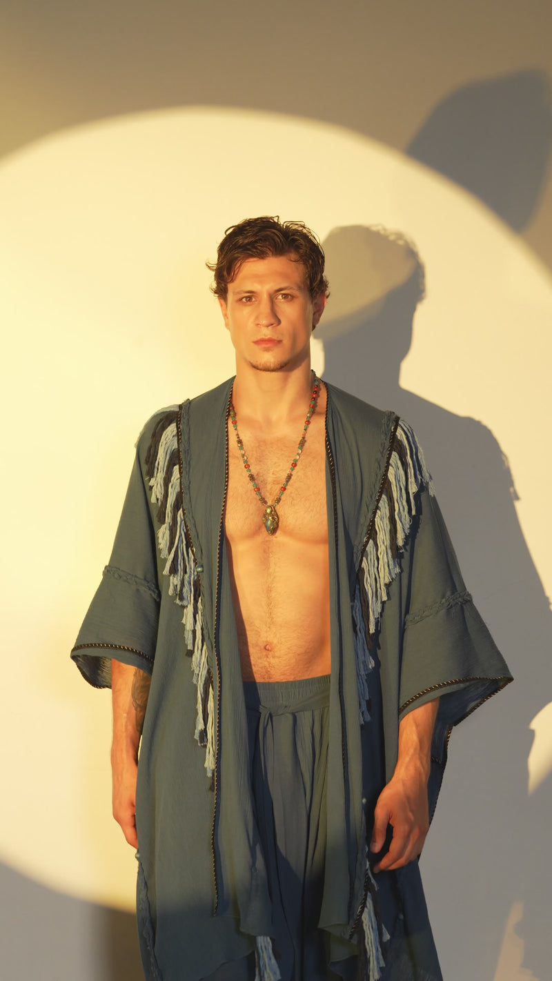 Boho chic poncho for men, crafted from navy blue organic cotton with fringe and braided details, perfect for festivals or casual shamanic-inspired style.